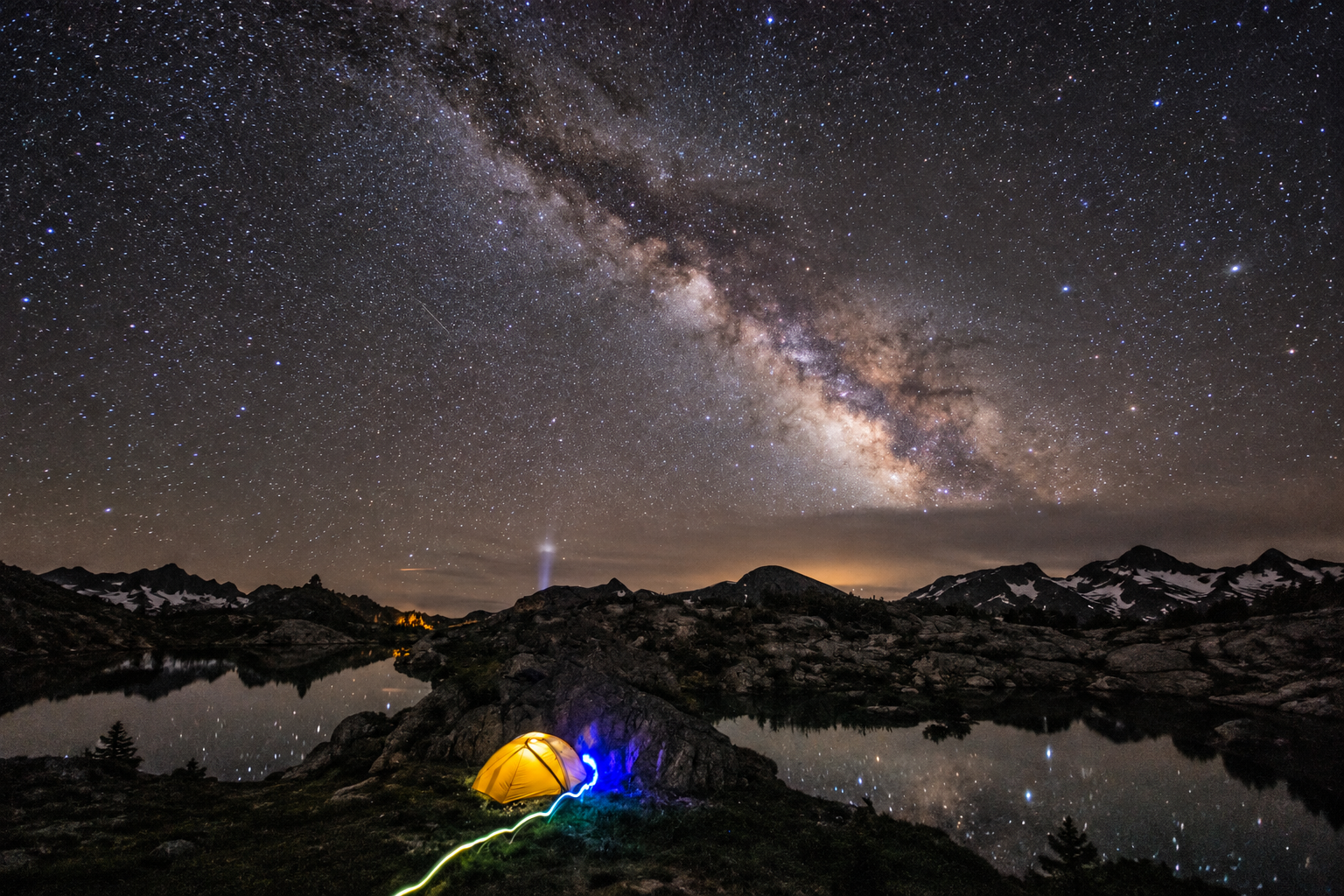 The Milky Way above an alpine campsite and lake, with AI-extended landscape surroundings.